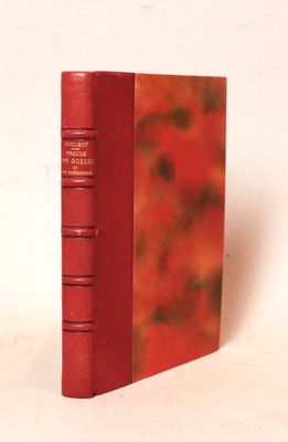 un vieux livre rouge posé sur une surface blanche