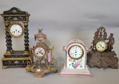 quatre horloges différentes posées sur une table, sur fond blanc