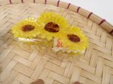 three yellow sunflowers in a clear vase on a wicker tray