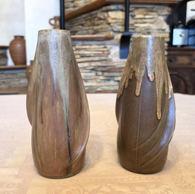 deux vases posés sur une table, avec un mur de pierre en arrière-plan