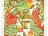 a close up of a green and red bird on a branch with leaves