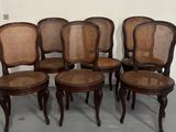 six chaises à assise en osier sont alignées en rangée