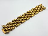 gros plan d'un bracelet en or sur une surface blanche