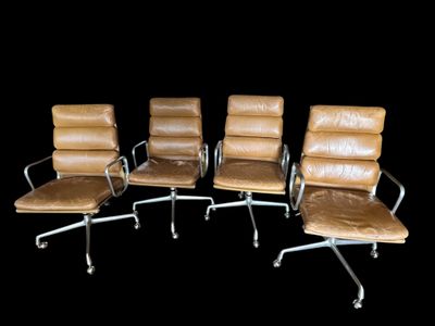 quatre fauteuils de bureau en cuir marron alignés sur un fond noir