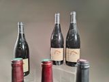 several bottles of wine are lined up on a clear shelf