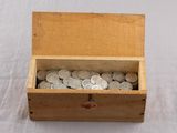 a wooden box filled with silver coins on a white surface
