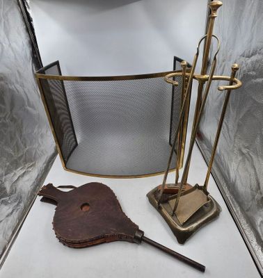 une cheminée équipée d'un pare-étincelles en métal sur lequel est posé un ensemble d'outils