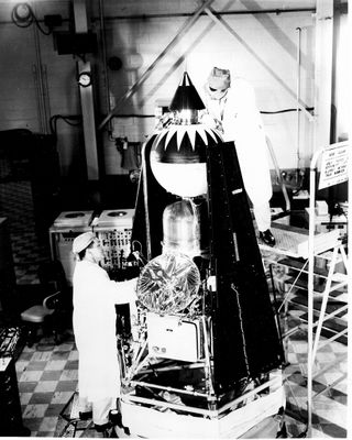 une vieille photo en noir et blanc d'un homme debout à côté d'une fusée spatiale