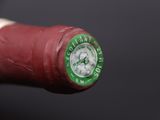 a close up of a red wine bottle with a green cap