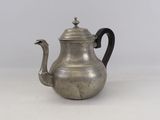 an antique silver teapot with a black handle on a white surface
