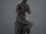 a bronze statue of a woman sitting on a tree stump