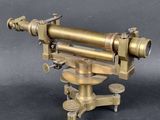 an antique brass telescope on a tripod stand on a grey background