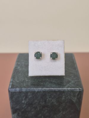 a pair of emerald earrings on a marble block