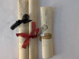 two rolled up scrolls with a red ribbon tied to them
