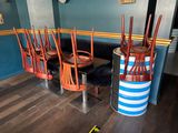 plusieurs chaises et une table dans une pièce où est accrochée une horloge au mur