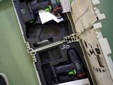 une boîte remplie d'outils posée par terre, près des pieds d'une personne