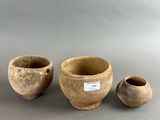 three small clay pots and two smaller clay pots on a gray surface
