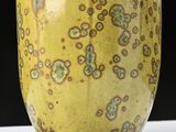 a close up of a yellow vase on a table