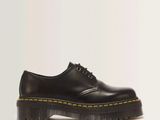 black dr martenshoes with yellow laces on a white background