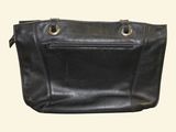 black leather handbag with metal handles and zippers on a white background