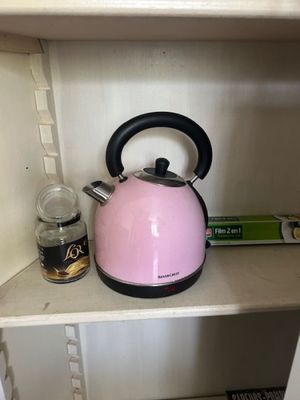 a pink tea kettle sitting on a shelf in a cupboard