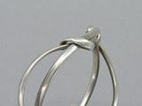 silver ring with a knot around the middle and a pearl in the middle