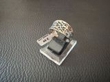 a silver ring with a tag on it sitting on a leather surface