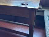 a wooden bench in the corner of a room next to a window
