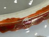 a white bowl with a red and gold decoration on it