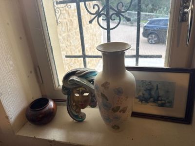 a white vase sitting on a window sill next to a picture