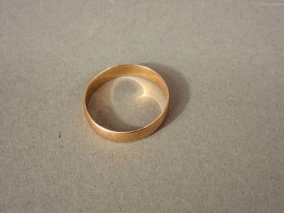 une bague en or posée sur une table, sur laquelle se projette une ombre