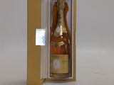 une bouteille de champagne dans un coffret, posée sur une surface blanche