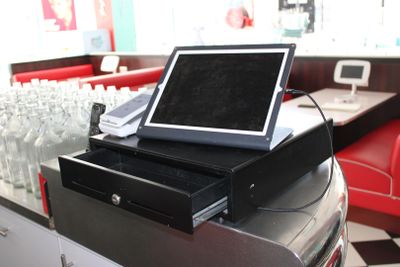 un ordinateur portable posé sur une caisse enregistreuse dans un snack-bar
