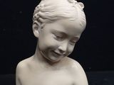 a small white statue of a child on a black surface