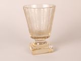 a glass vase with a gold base on a white background