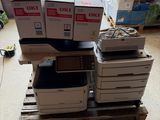 une pile d'imprimantes posée sur une palette dans un garage