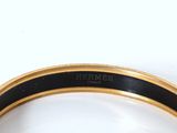 a close up of a black and gold bracelet on a white surface