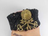 a doll wearing a hat with a gold broocher on it
