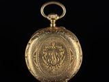 an old gold pocket watch with a chain on a black background