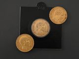 three gold coins are sitting on top of a black surface