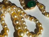 pearl necklace with a green glass bead and a gold clasp