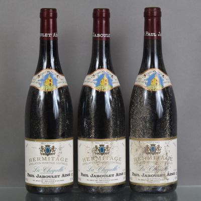 three bottles of wine are lined up on a glass table