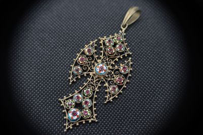 a close up of a gold pendant with colorful stones on it