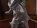 une statue représentant un garçon tenant un oiseau sur une table