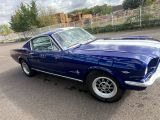 une Mustang bleue garée sur un parking, près d'une clôture