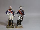 pair of figurines of two men in uniforms with guns