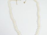 a close up of a white necklace with pearls on a white background