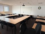 des tables et des chaises dans une salle de classe, avec une horloge accrochée au mur