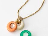 two necklaces with rings on a gold chain on a white surface