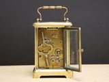 a small gold clock with a glass door on a table